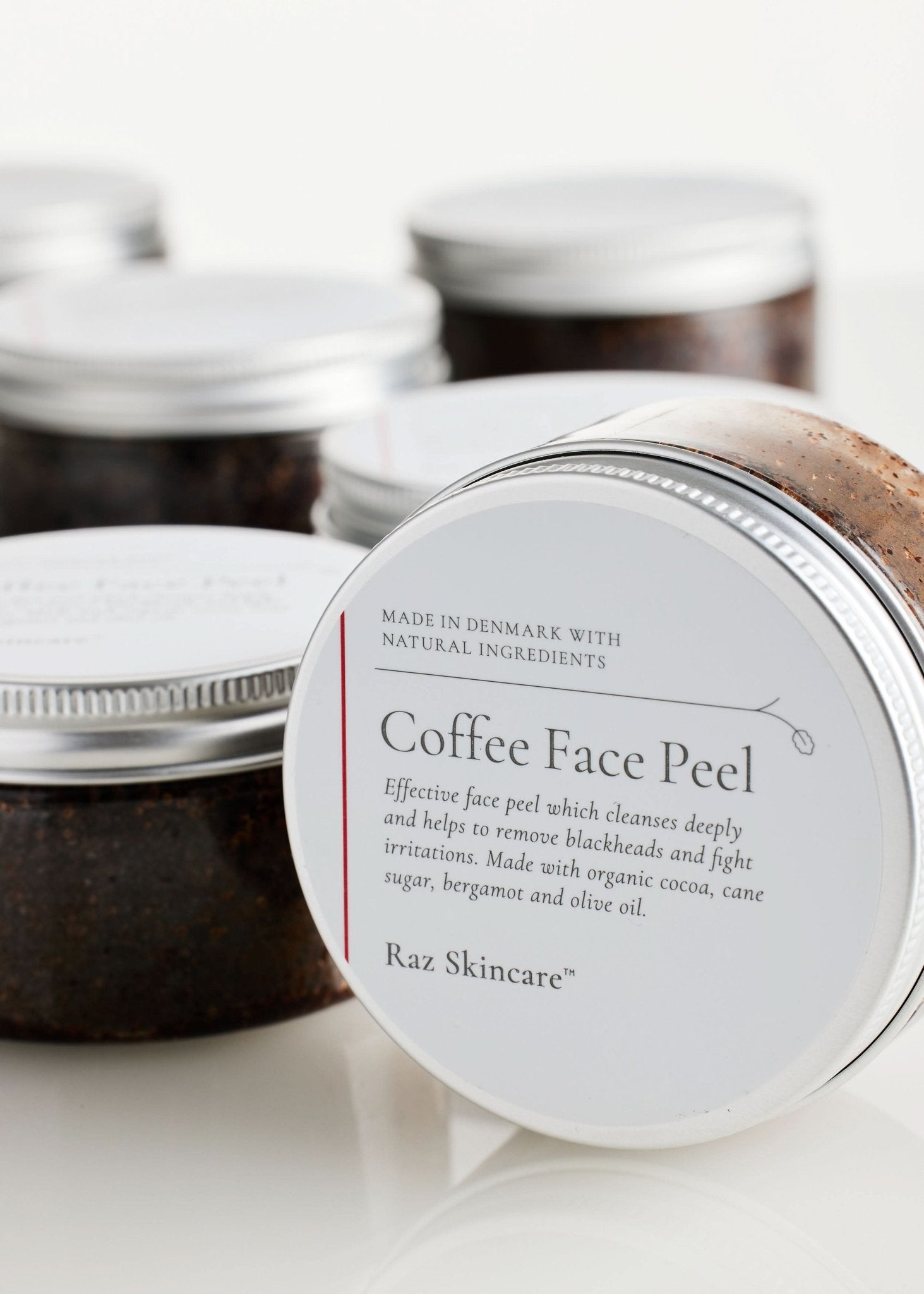 Coffee Face Peel 100g - Raz Skincare - Raz Skincare Coffee Face Peel i krukke med sølvlåg, omgivet af flere af de samme krukker i baggrunden