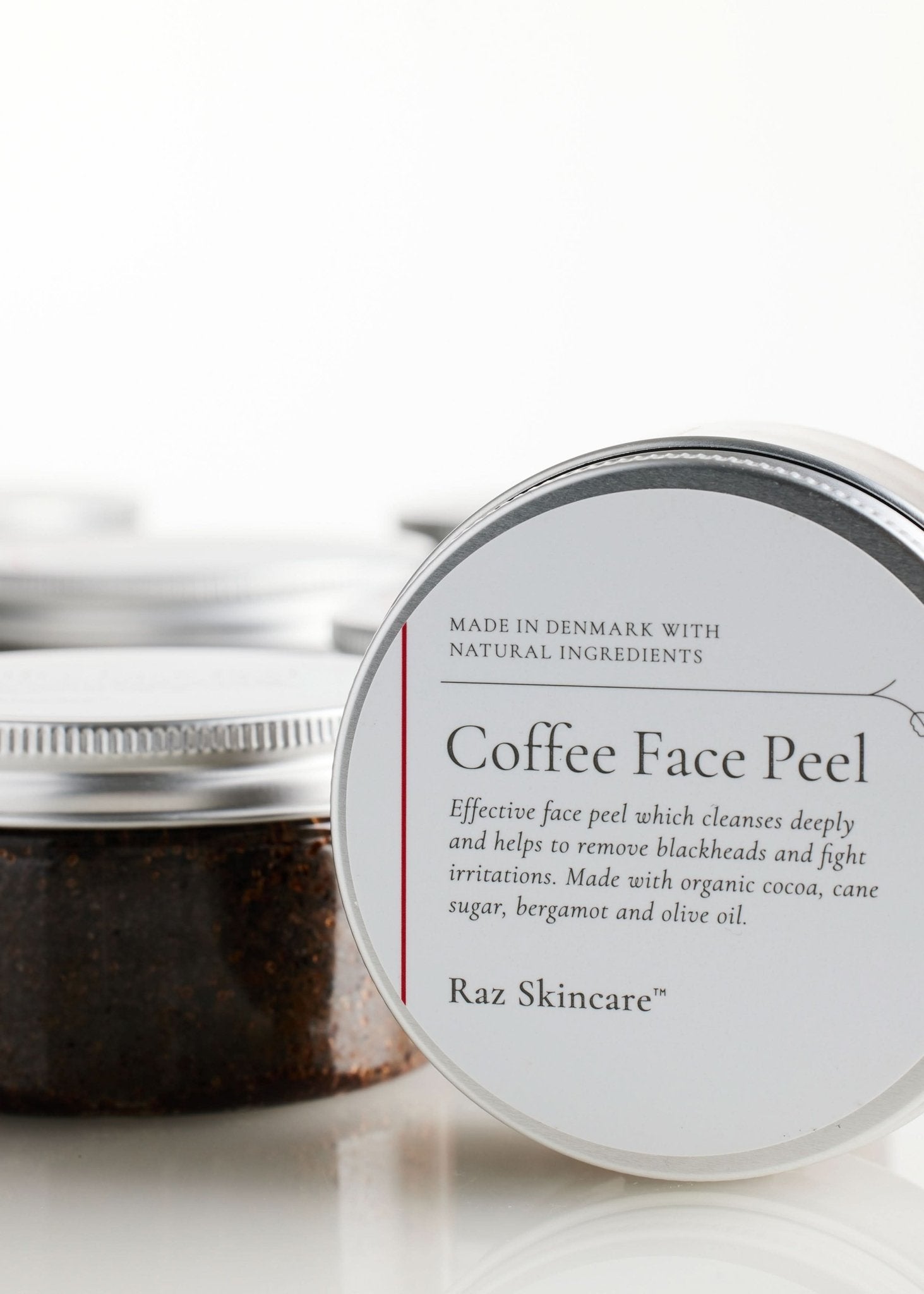 Coffee Face Peel 100g - Raz Skincare - Raz Skincare Coffee Face Peel i krukke med sølvlåg, omgivet af flere identiske krukker i baggrunden