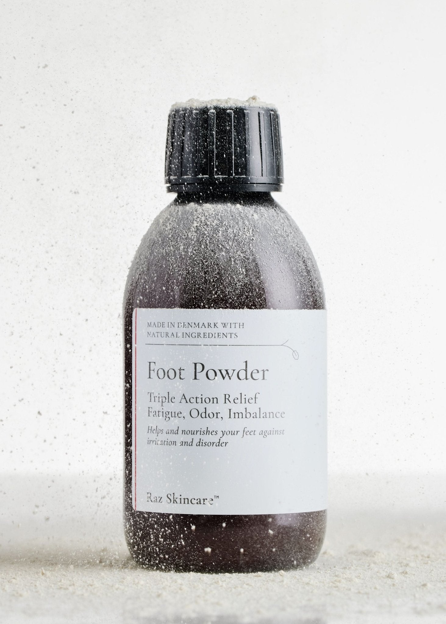 Foot Powder 75g - Raz Skincare - Raz Skincare Foot Powder i brun flaske med sort låg, dækket af dryssende pulverpartikler, Hele flasken